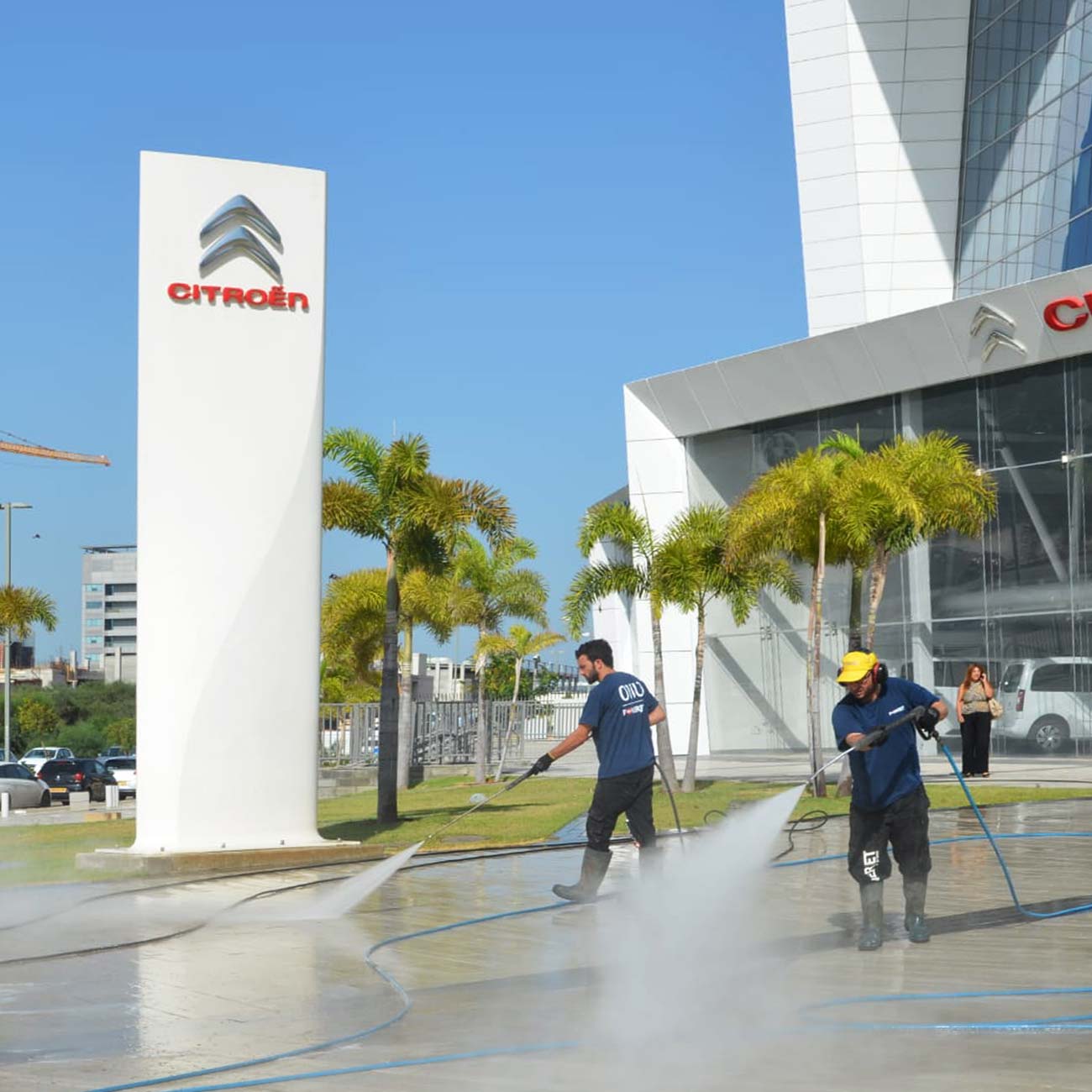 Citroen car dealership employees spray the pavement with high-pressure washing machines