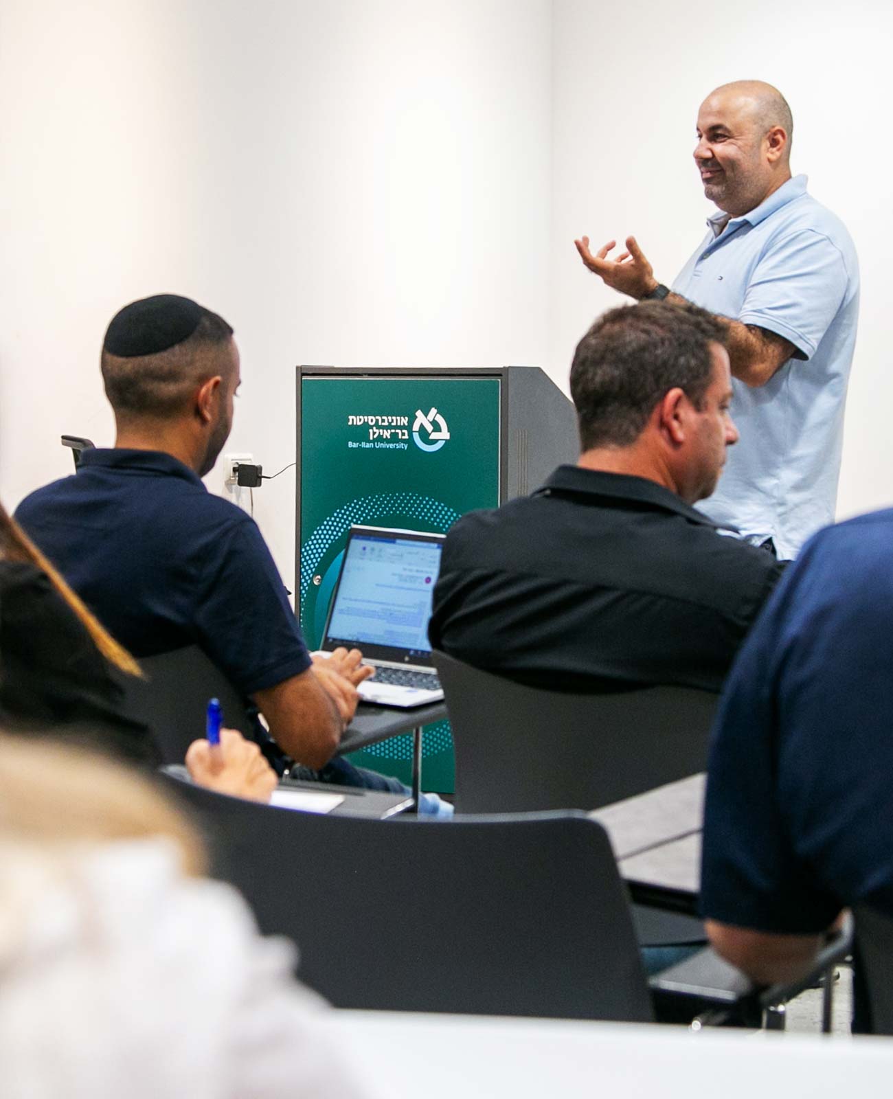פרופסור גבר מדבר בפני הכיתה מעל דוכן הופעות