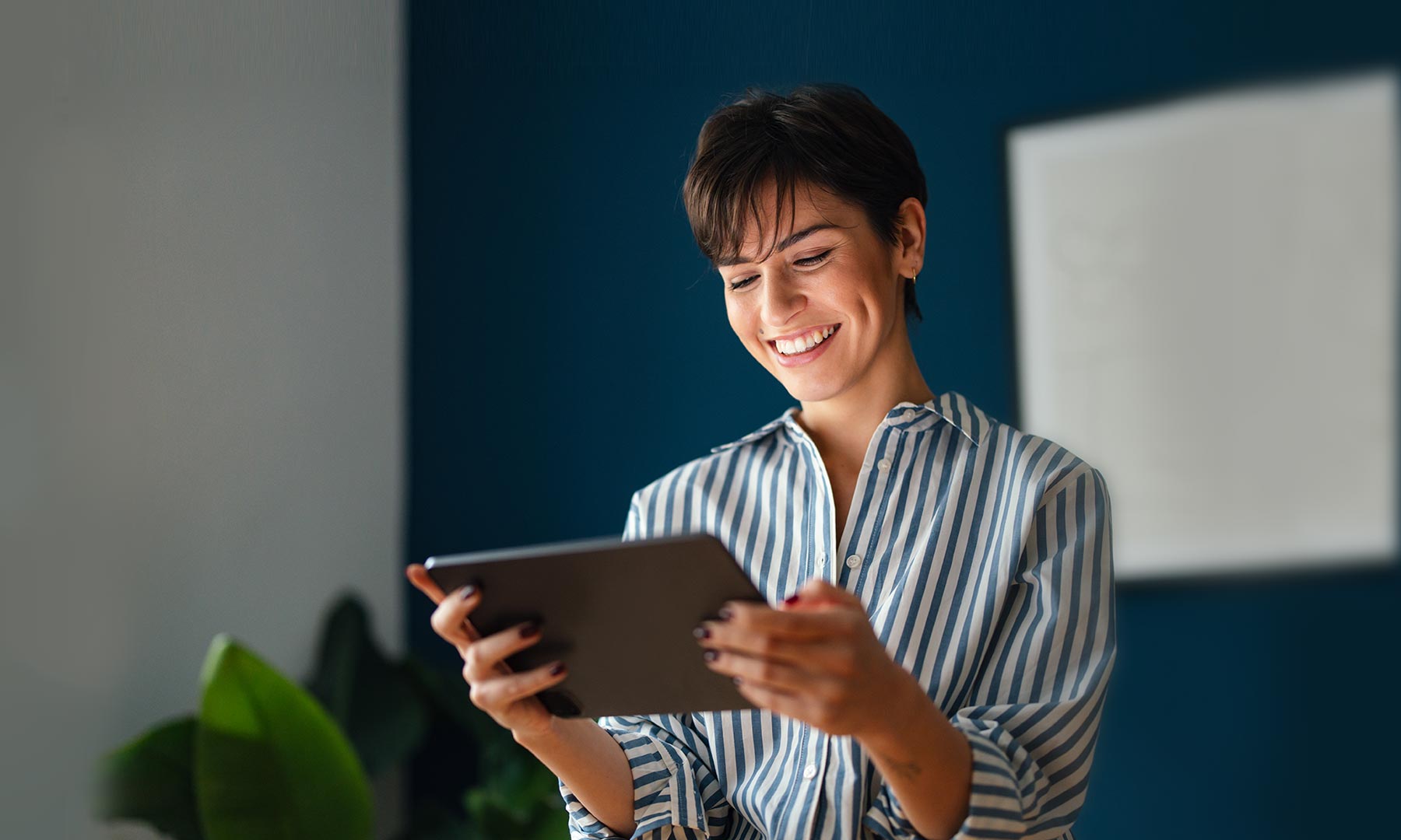 Young brunette woman smiling while holding a tablet