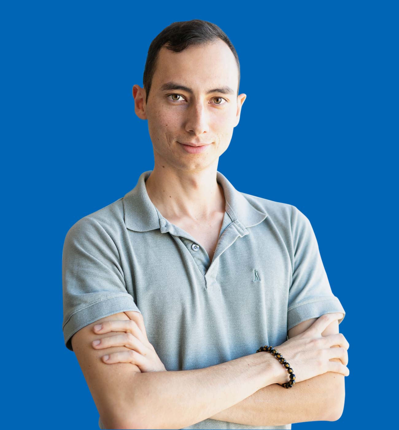 A young brunette man with a dark blue collared shirt smiling