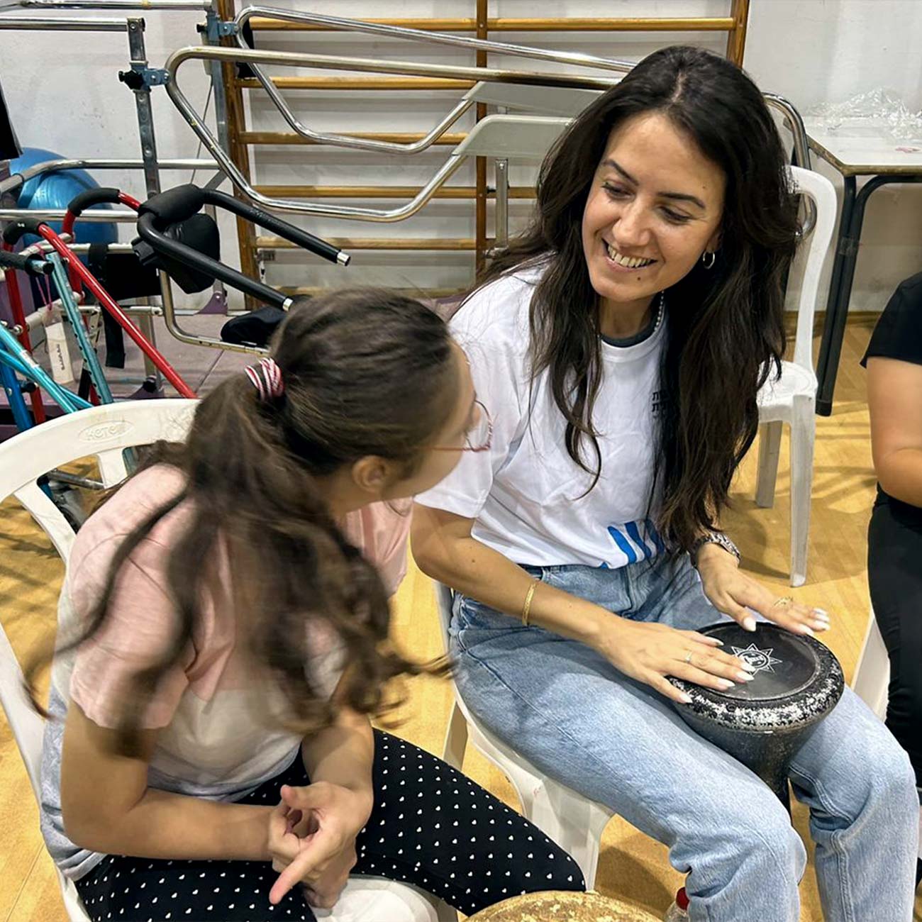 A young woman sits with a child near a drum circle