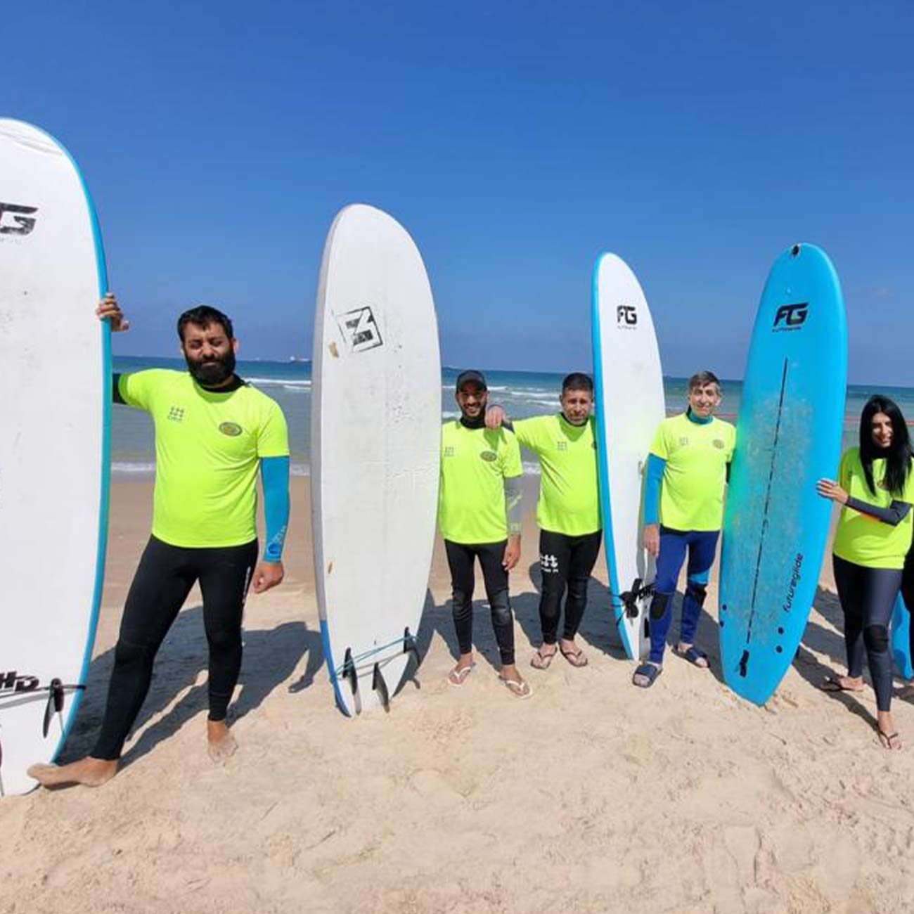 Electra FM employees pose with surfboards at the beach