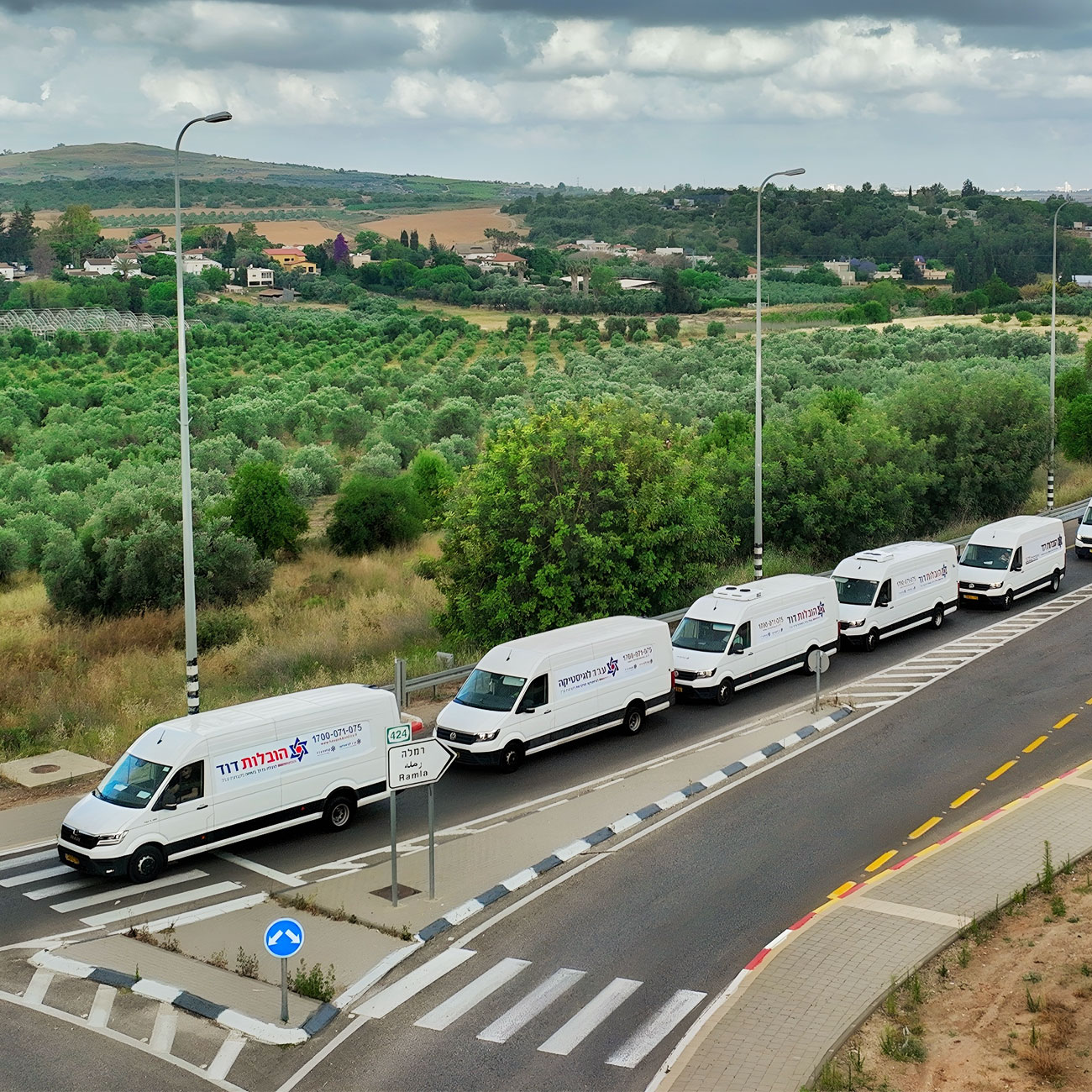 A fleet of ARD Group moving vans parked beside agricultural fields near Ramla.