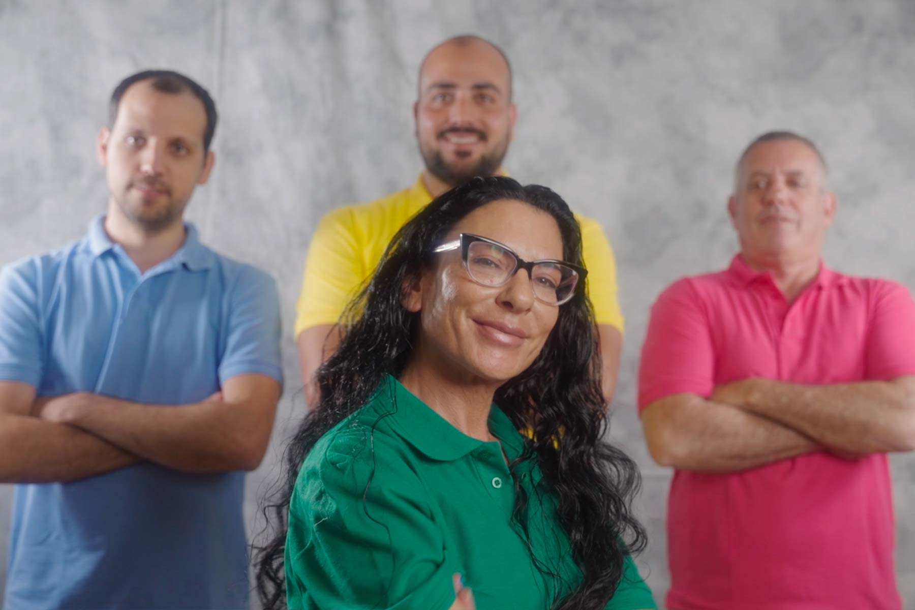 A smiling female worker in the foreground and three workers in the background