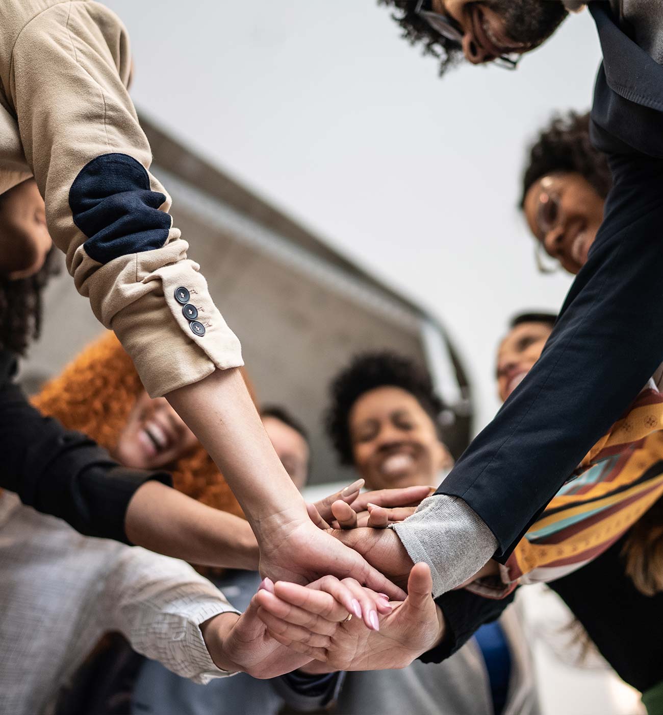 A group of people in a circle put their hands together