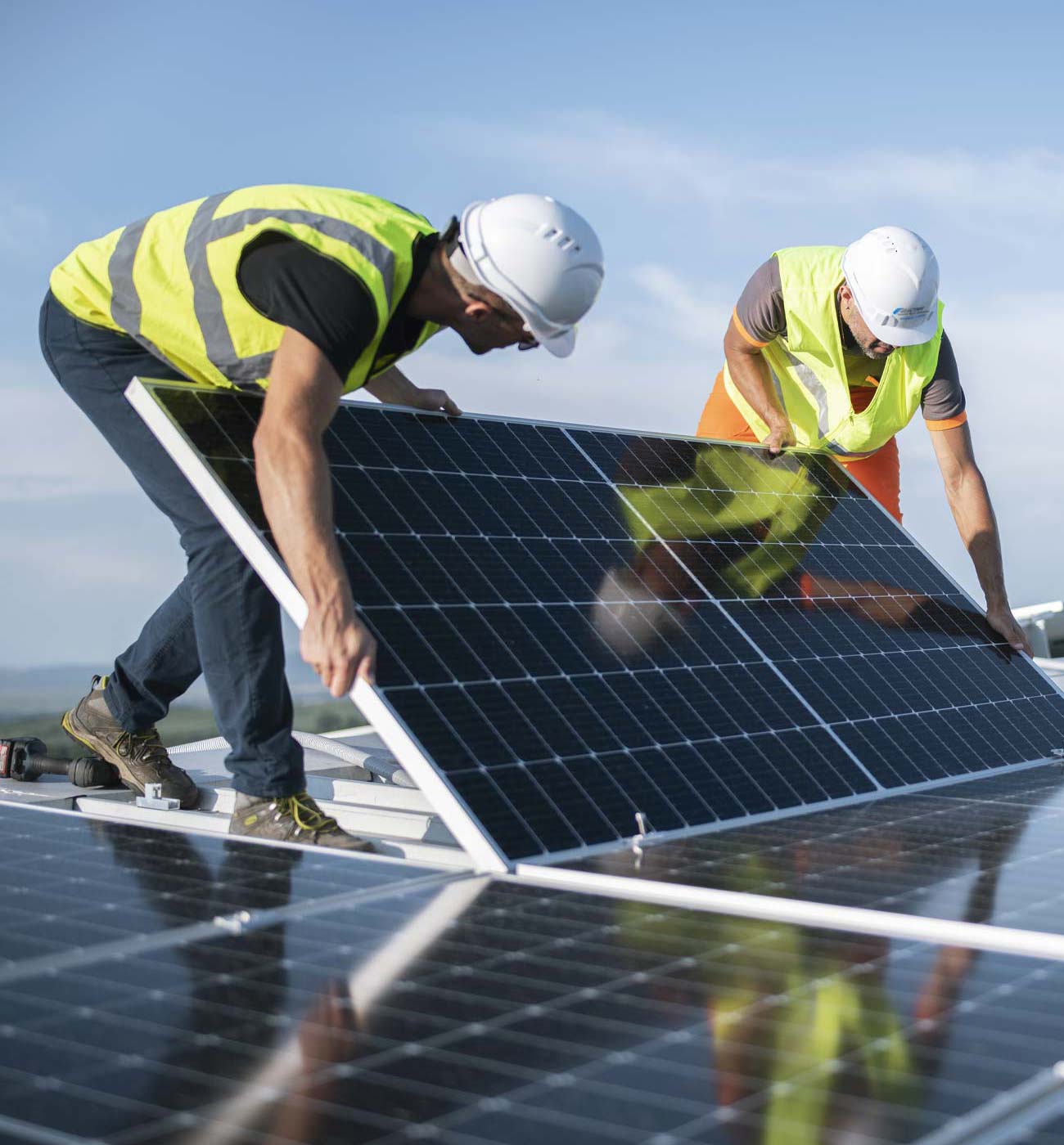Two Electra FM workers set up a solar panel on a roof